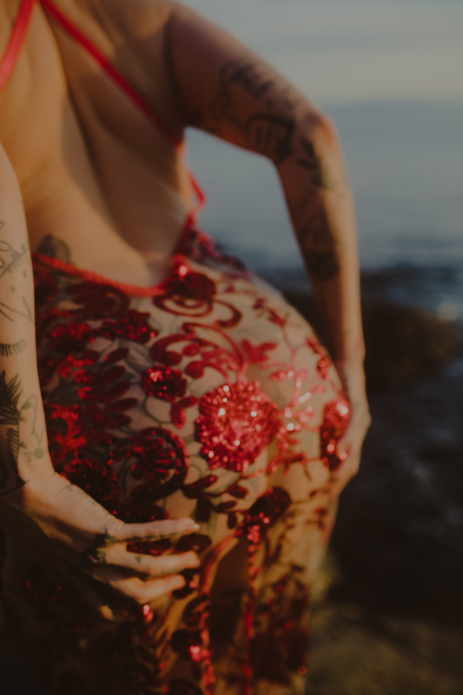 A close up of Rae De Rosa in a sheer, sequinned dress with her hands cupping her ass.