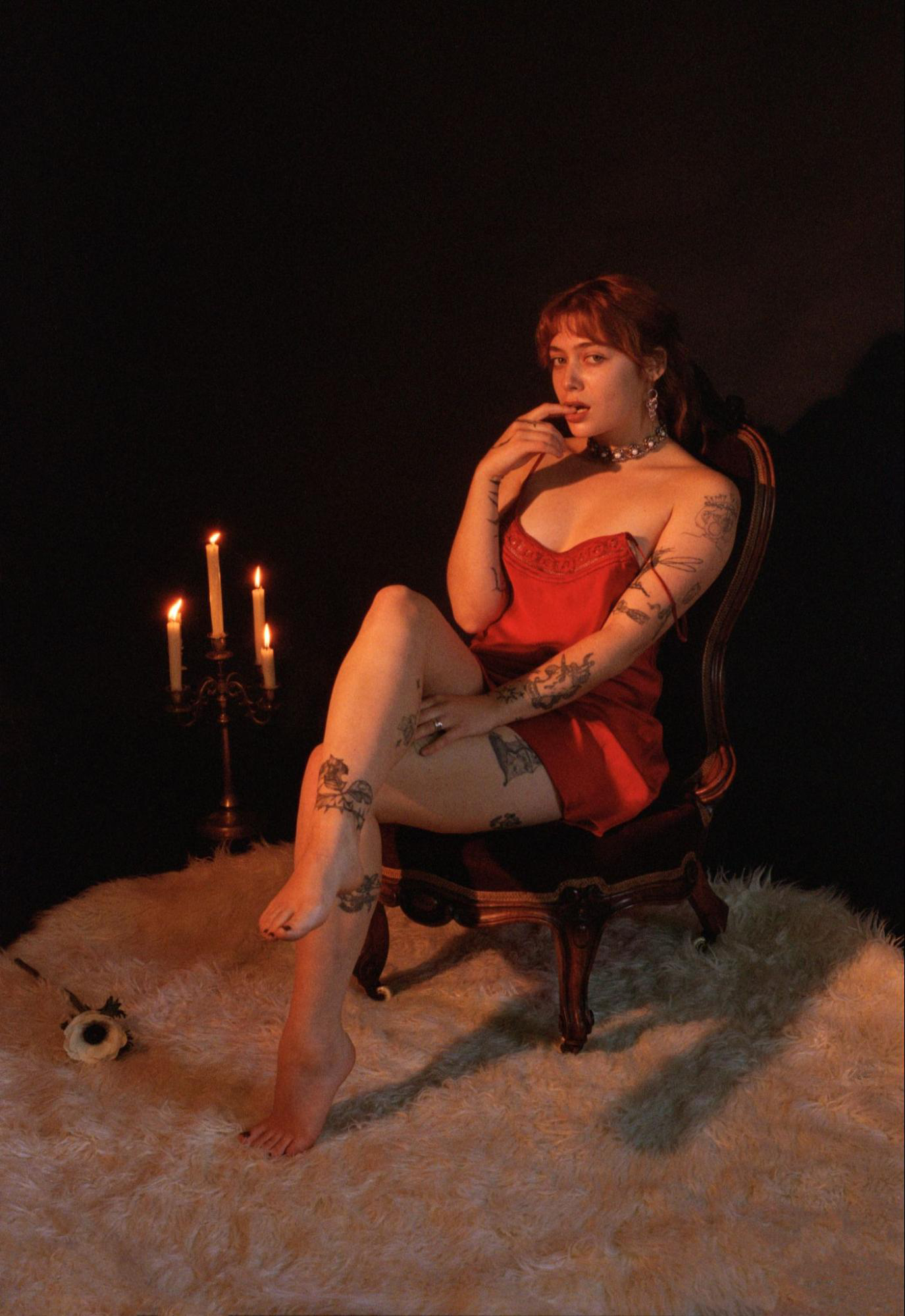 Seattle Escort Chiara Novo sits in a candle-lit room, dressed in a red negligee.