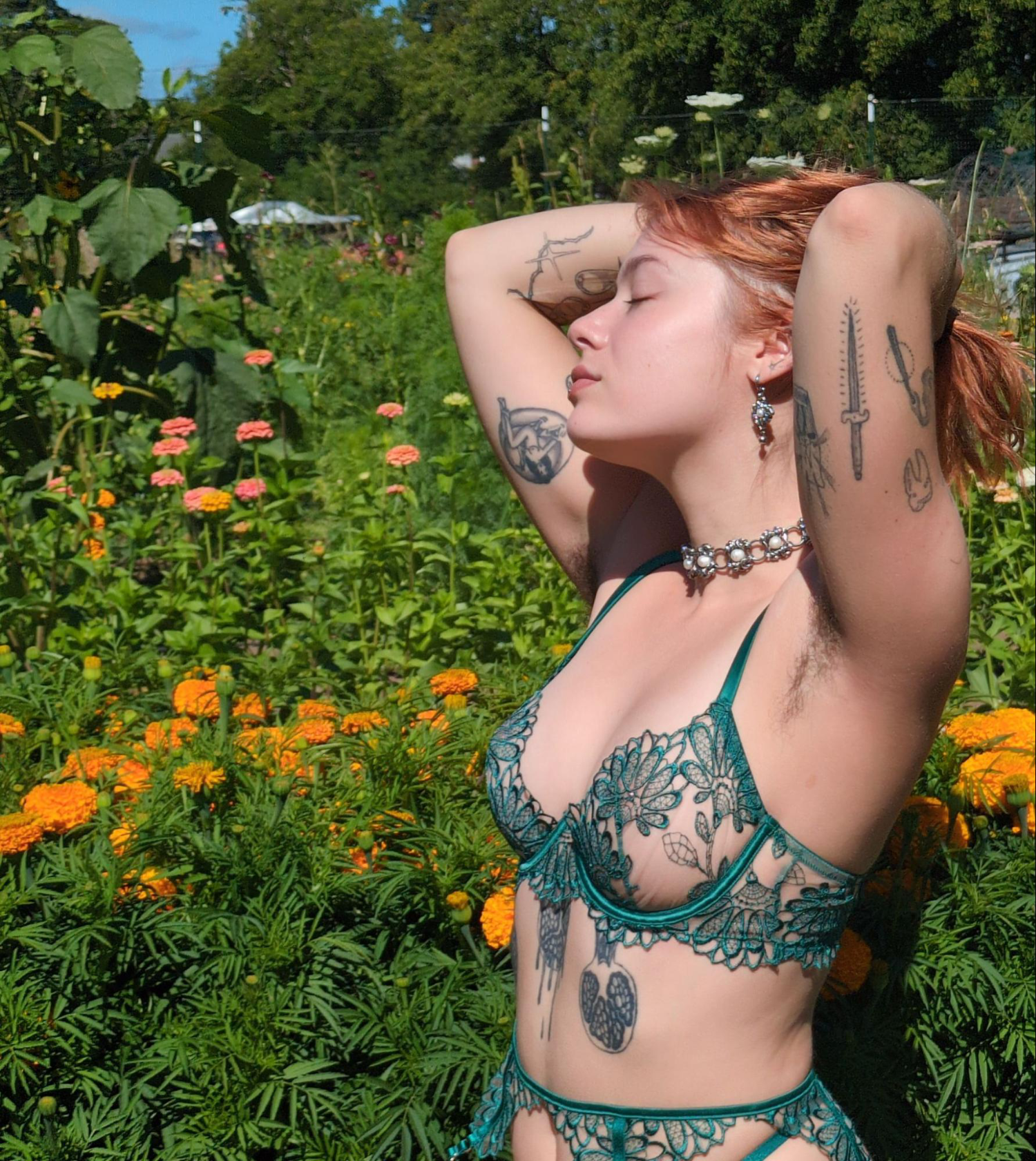 Seattle Escort Chiara Novo stands in a field of flowers, wearing green lingerie.